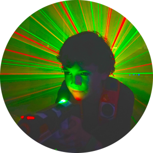 Night Time Laser Tag Birthday Parties for Teen Boys and Girls. This picture shows red and green lasers radiating behind a boy with his face illuminated by a green light.