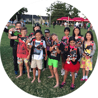 Happy kids group at a School Fete, all posing for a laser tag photo. Laser Tag is a great Fundraiser and attracts the crowds.